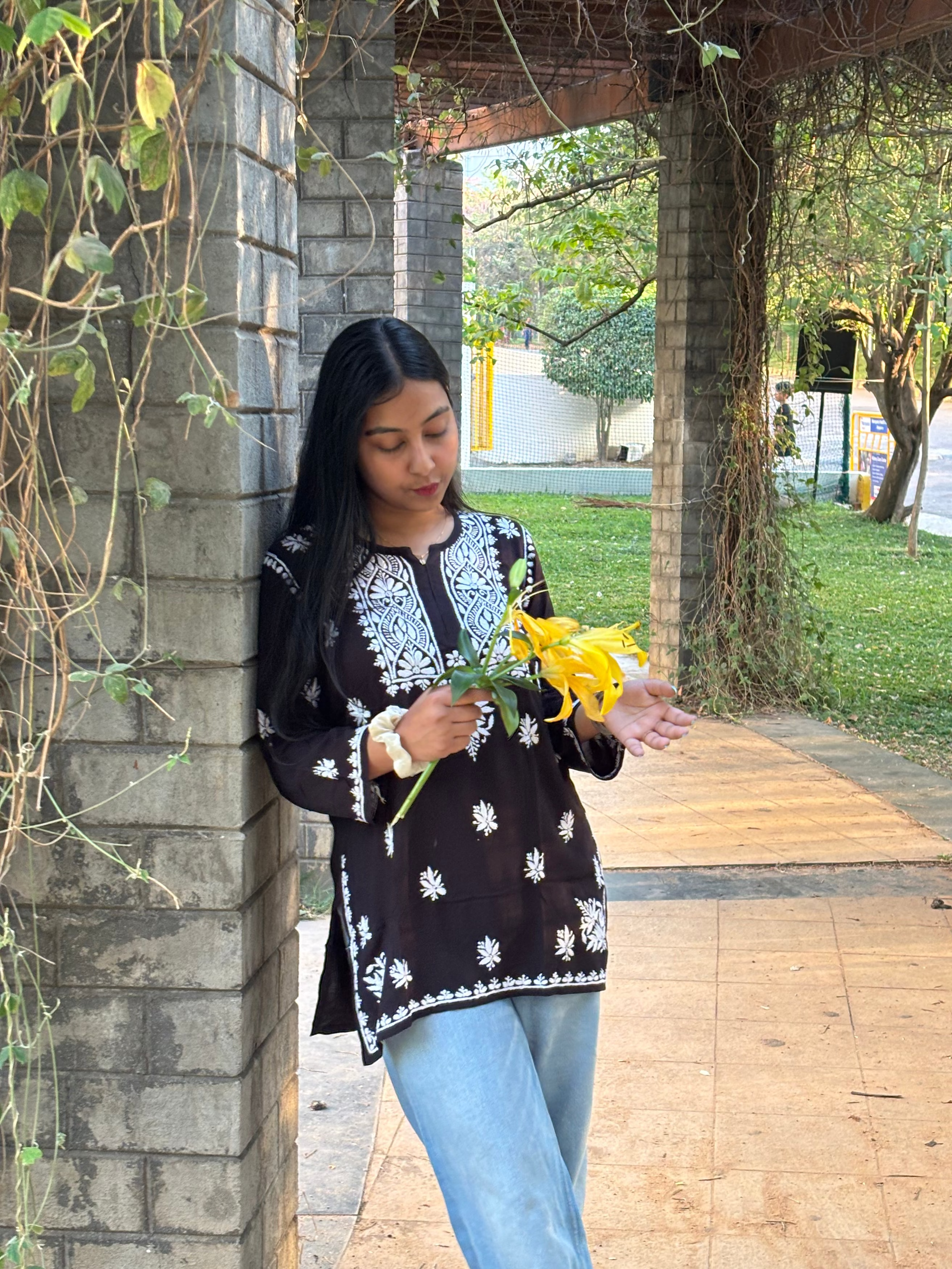 Woman holding yellow flowers standing under a stone archway